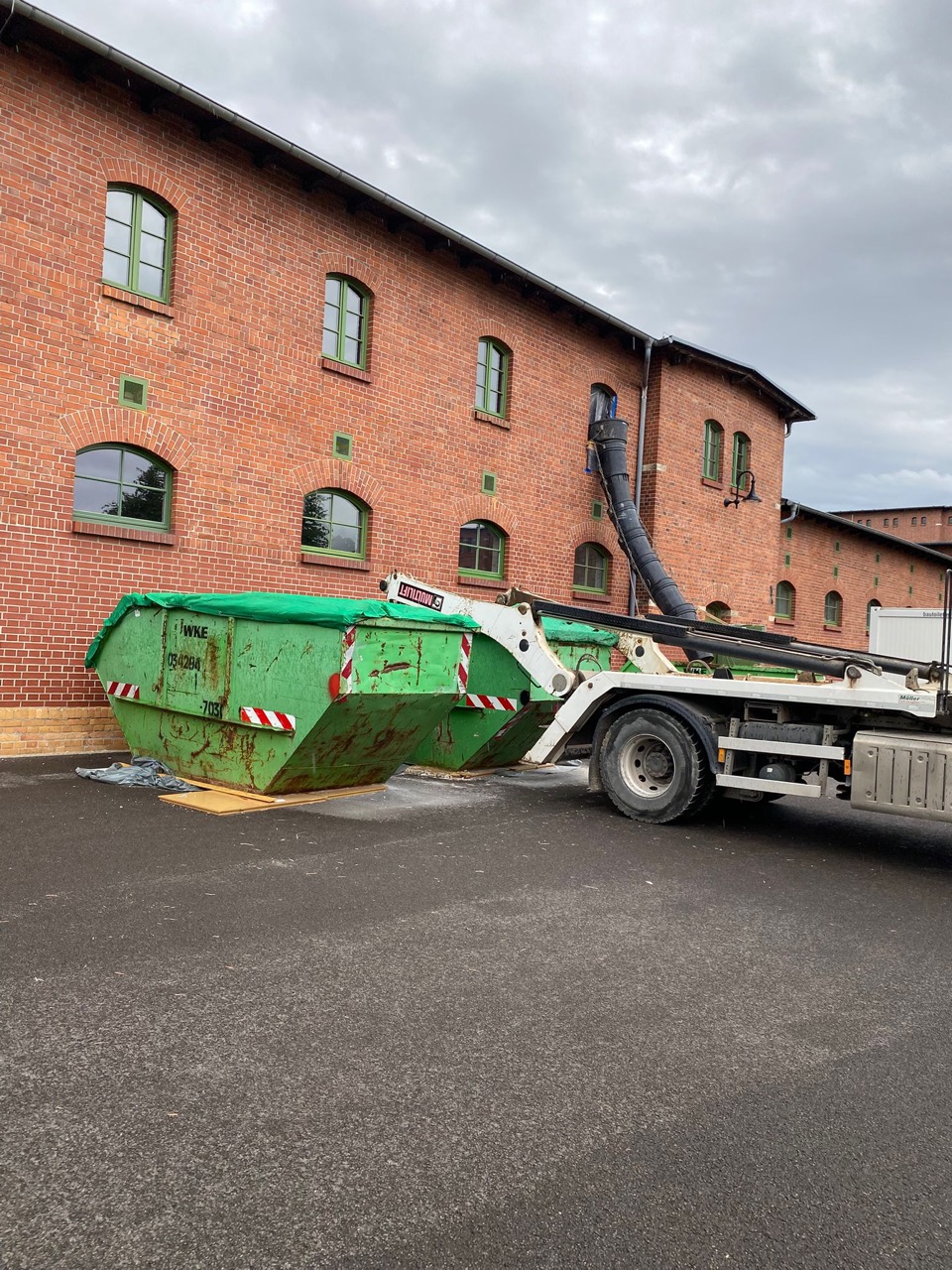 Container und Absetzkipper vor einem Baustellengebäude